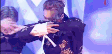 a man in a purple suit is dancing on a stage with a woman behind him .