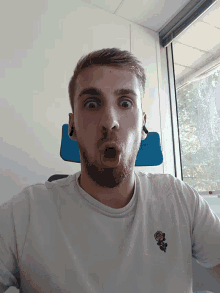 a man with a beard is wearing a white shirt with a skull and crossbones embroidered on it