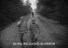 two men in striped prison uniforms are running down a road .