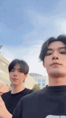 a couple of young men are standing next to each other in front of a building .