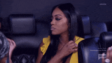 a woman in a yellow top is sitting in a chair with the bravo logo on the bottom