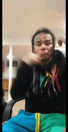 a man with a tattoo on his face is sitting in a chair and making a face