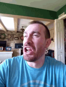 a man with a beard wearing a blue shirt with the letter p on it