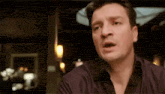 a man is making a funny face while sitting at a table in a restaurant .