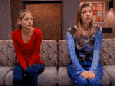 a woman in a red shirt sits next to another woman in a blue tie dye shirt