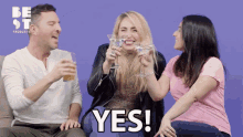a group of people are sitting on a couch and one of them is holding a martini and says yes