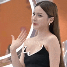 a woman wearing a black dress with pearls on it is giving a thumbs up