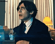 a man in a suit and tie is standing in front of a window in an office .