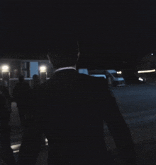 a man in a suit is walking down a dark street