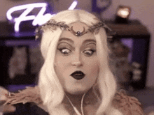 a woman is wearing a wig and a crown on her head and making a funny face .