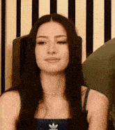 a woman with long hair is wearing a denim top and a choker necklace .