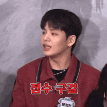 a young man wearing a red jacket and a name tag that says ' eun ' on it
