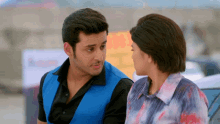 a man in a blue vest looks at a woman in a blue shirt