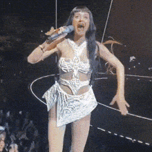 a woman singing into a microphone with her mouth wide open