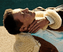 a man wearing a sweater and a jacket is laying down
