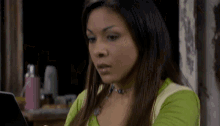 a woman in a green shirt is using a laptop computer