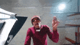 a man wearing a red sweater and a bandana is pointing at something .