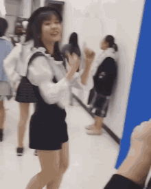 a woman in a white shirt and black shorts is standing in a hallway with other people