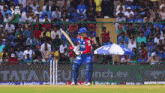 a cricket player is batting in front of a banner that says punch