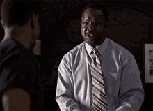 a man in a blue shirt and tie is talking to another man in a black shirt with the word si on it