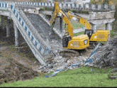 a cat excavator is demolishing a bridge that has fallen over