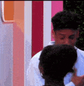 a man and woman are standing next to each other and the woman is touching the man 's face .