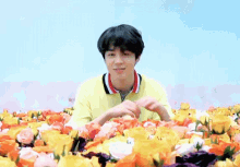 a man in a yellow shirt is surrounded by flowers