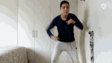 a man in a blue shirt and white pants is jumping in the air in a room .