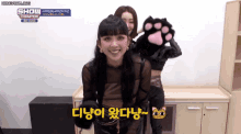 a woman is holding a cat paw while another woman looks on