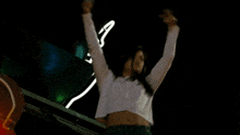 a woman in a crop top is dancing in front of a sign that says ' coca cola ' on it