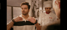 a man in a black and white striped shirt is talking to a chef