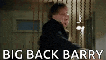 a man in a suit is standing in a room with the words `` big back barry '' written on the screen .