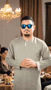 a man wearing sunglasses stands in front of a table full of people