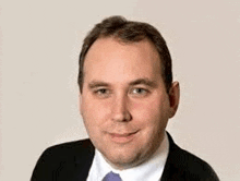 a man wearing a suit and tie is smiling for the camera .