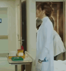 a woman in a lab coat is standing in a hospital hallway
