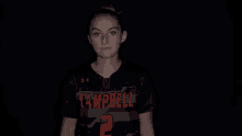 a woman wearing a campbell jersey stands with her arms crossed