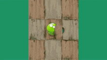 a green cartoon character is standing on a wooden wall .