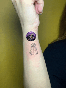 a woman has a small tattoo of a spider man on her wrist