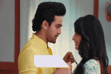 a man in a yellow shirt is touching a woman 's neck