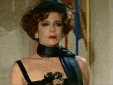 a woman wearing a black dress and a black scarf looks at the camera