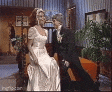 a woman in a wedding dress sits next to a man in a suit on a couch ..