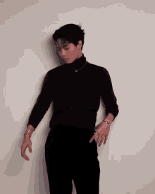 a man wearing a black turtleneck and a necklace with the letter r on it