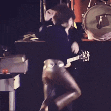 a man is playing a guitar in front of a drum