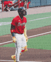 a baseball player wearing a red jersey that says braves on it