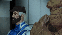 a man with a beard is standing next to a statue