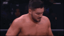 a shirtless wrestler in a ring with the aew logo on the bottom left
