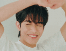 a young man in a white shirt is making a funny face with his hands in the air .