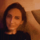 a woman is sitting on a couch and looking at the camera with a blurred background .