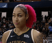 a woman with pink hair is wearing a jersey with car max on it