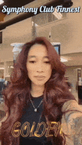 a woman with long red hair is standing in front of a sign that says symphony club funnest golden !!